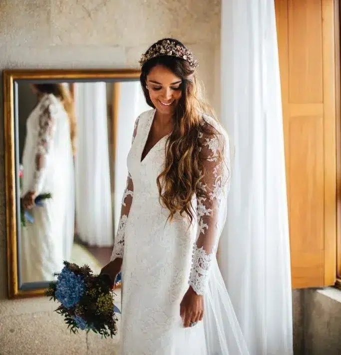 Novia feliz preparada para su gran día con maquillaje natural y el cabello suelto con ondas y una diadema de flores