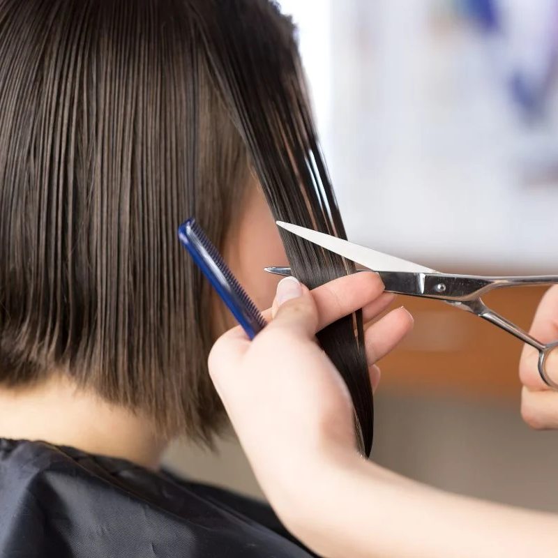 Peluquera realizándole un corte de pelo a una mujer