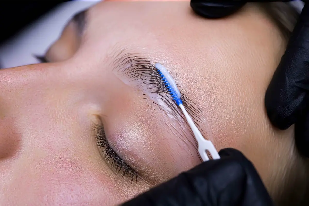 Profesional realizando un laminado de cejas a una mujer